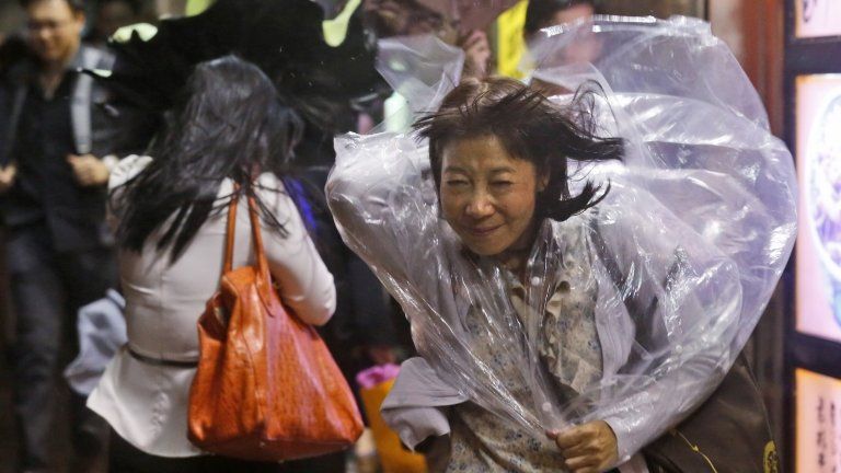 A woman braves strong wind in Hong Kong on 15 September 2014