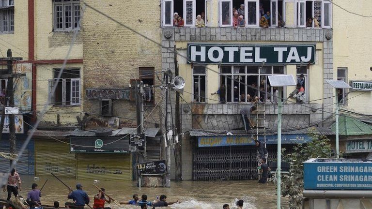 Flood victims watch from the windows of a hotel as Kashmiri volunteers try to get relief material across to them in the city center of Srinagar, India, Friday, Sept. 12, 2014.