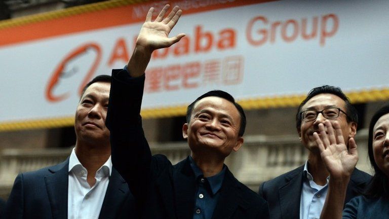 Jack Ma waves and smiles outside the New York stock exchange in front of an Alibaba sign