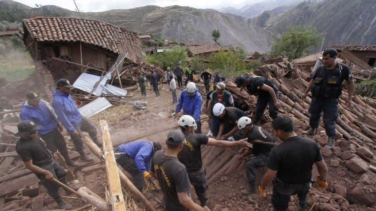 Rescue workers search for bodies in the ruins of a collapsed house after a 4.9-magnitude earthquake shook a village near the city of Cuzco, Peru, on 28 September 2014