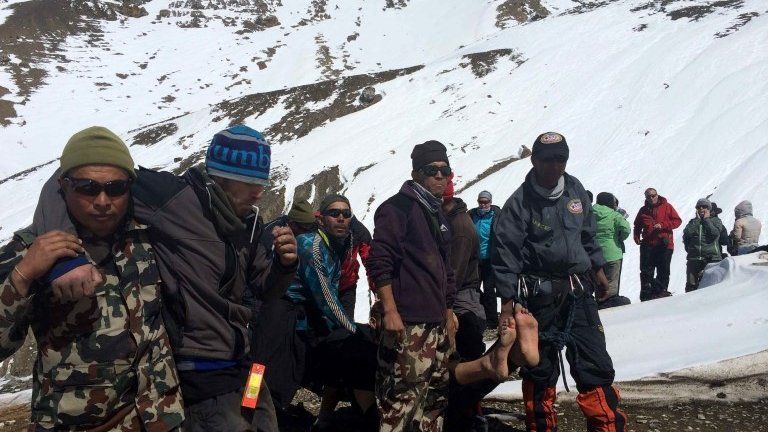 A survivor injured in a snowstorm is carried on a stretcher by Nepal Army personnel to an army helicopter in the Manang district along the Annapurna Circuit Trek, 17 October 2014