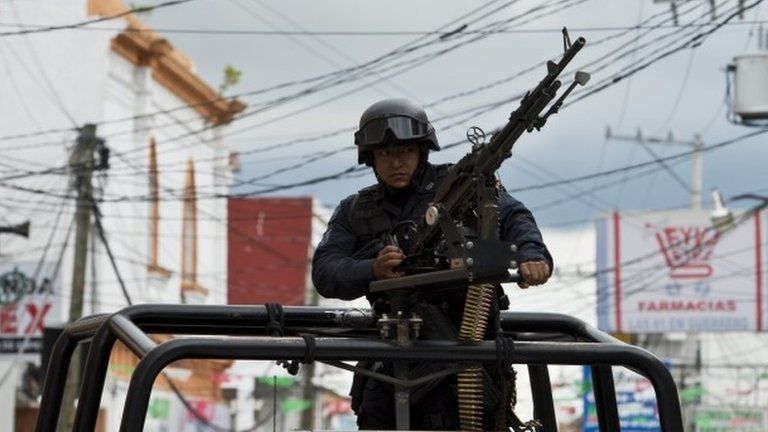 A member of the Mexican Federal Police stands guard in a street of Teloloapan on 19 October, 2014.