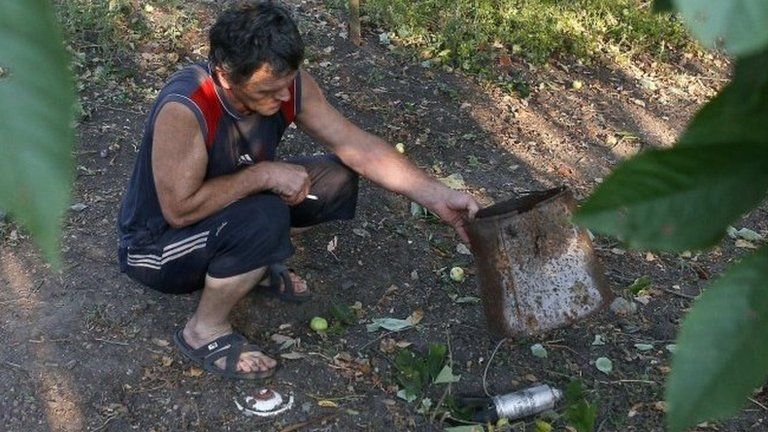 A man shows a dud cluster bomblet in Donetsk, Ukraine, 25 August