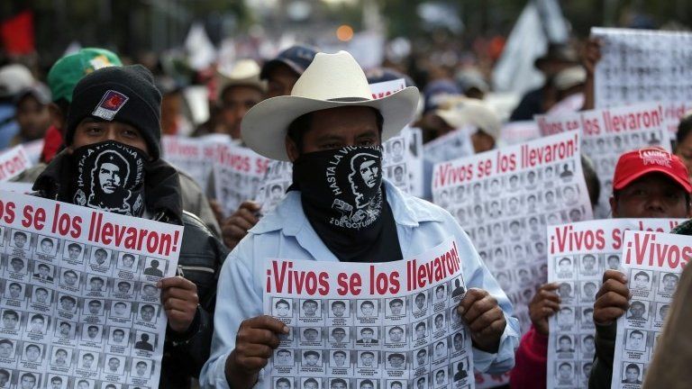 People march holding posters with the images of missing students that read in Spanish "They took them alive," to protest against the disappearance of 43 students from the Isidro Burgos rural teachers college in Mexico City on 22 October, 2014.