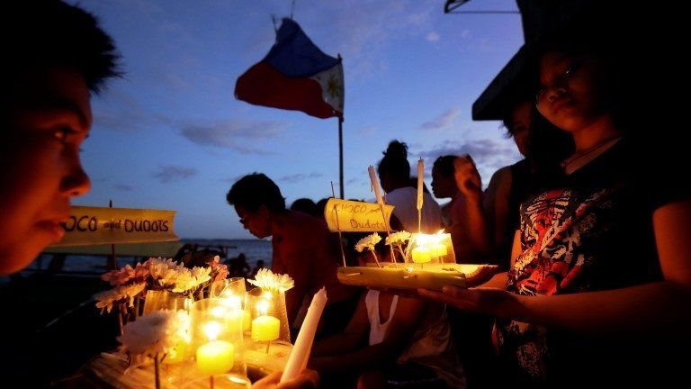 Filipinos gather to offer candles, prayers and flowers outside their makeshift houses in Tacloban City, Leyte province, Philippines, 08 November 2014