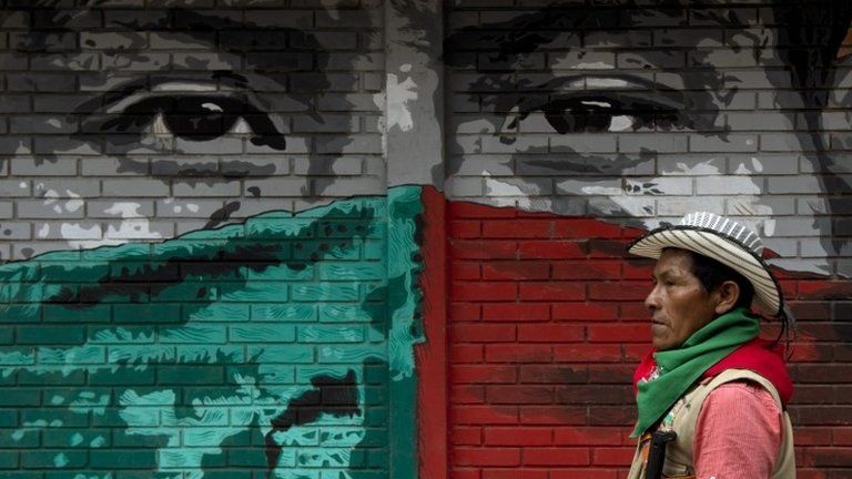 A Colombian Nasa native guard walks by a mural stencil on 9 November, 2014