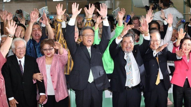 Former Naha mayor Takeshi Onaga (front C) and his supporters raise their hands in the air in celebration in Naha, the capital of Japan's southern island of Okinawa, 16 November 2014
