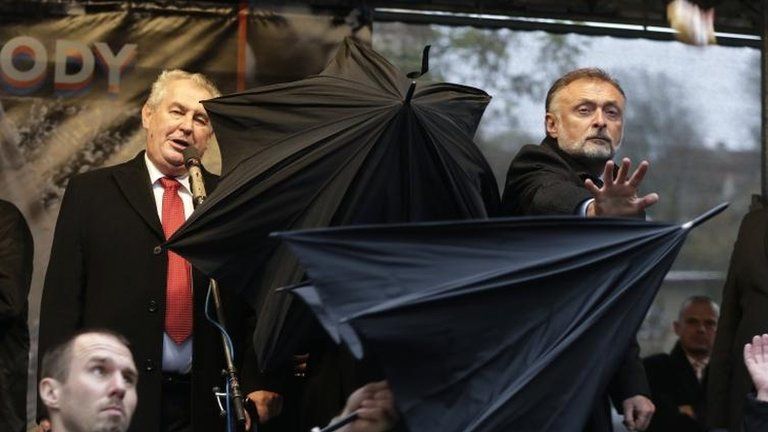 Security guards open umbrellas as people throw eggs and tomatoes at the President of Czech Republic, Milos Zeman in Prague, Czech Republic on 17 November 2014