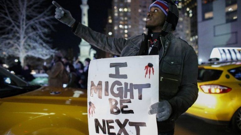 A man holds a sign as he takes part in a protest in New York after a grand jury decided not to indict New York Police Officer Daniel Pantaleo in Eric Garner's death on 3 December