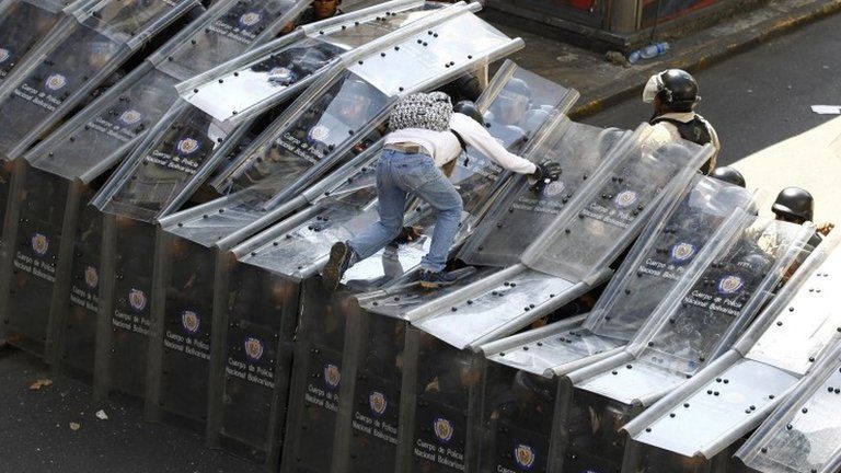 A protester scales police shields in Caracas, 12 February
