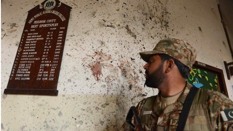 A Pakistani army soldier looks at a plaque listing the best sports students at the site of the militants' attack on the army-run school in Peshawar on 18 December 2014