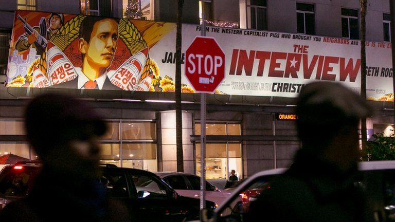 People walk past a banner for "The Interview" in Los Angeles, California, on 17 December 2014