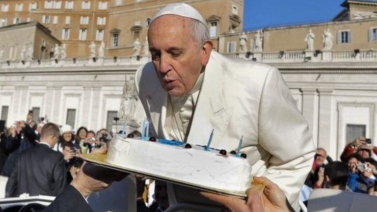 Pope Francis blows candles on a cake during his weekly general audience in St. Peter' Square at the Vatican, 17 December 2014