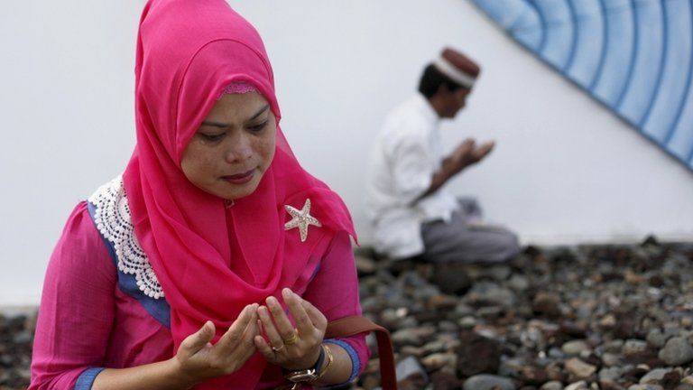 A woman prays at a mass grave in Aceh, Indonesia, 26 Dec