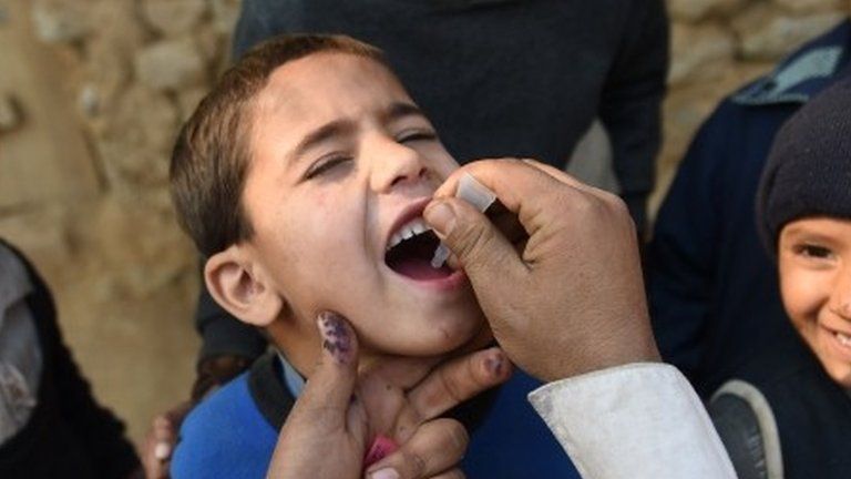 Pakistani polio vaccination worker Sher Khan (L) administers polio vaccine to a child in a poor neighbourhood that hosts Afghan refugees and internally displaced tribal people on the outskirts of Islamabad on December 29, 2014, during a vaccination campaign.