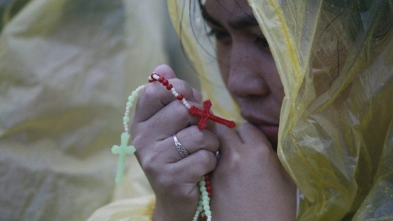 A woman prays while hearing a mass officiated by Pope Francis in Tacloban in the Philippines