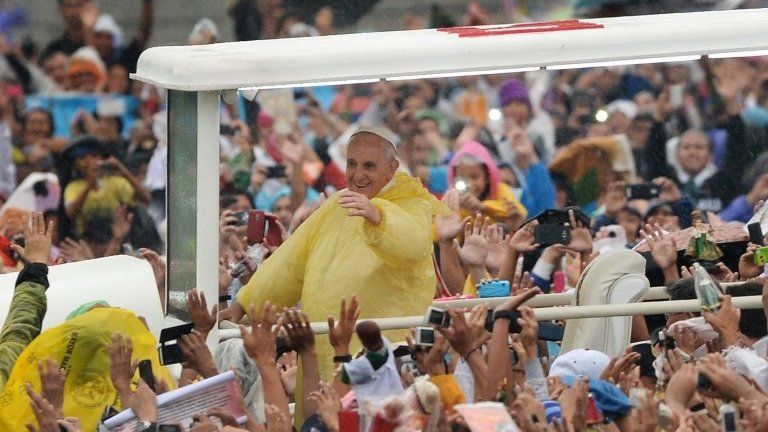 Pope Francis (C) greets worshippers as he arrives to celebrate a mass at a park in Manila, 18 January 2015