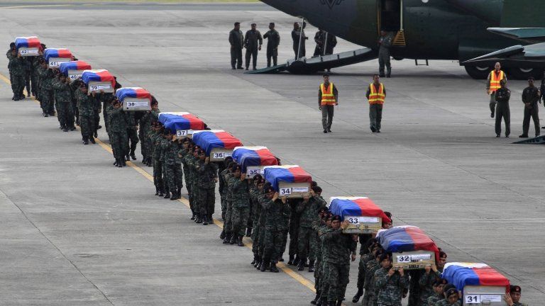 Members of the Philippine National Police's (PNP) Special Action Force (SAF) unit carry metal caskets containing the bodies of slain SAF police who were killed in Sunday's clash with Muslim rebels, upon arriving at Villamor Air Base in Pasay city, metro Manila on 29 January 2015