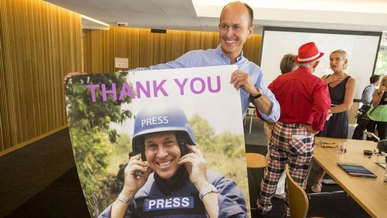 Peter Greste's brother Peter holds a poster of his brother as he celebrates the journalist's release at a press conference in Brisbane