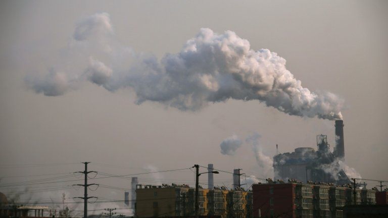 Smoke rises from a chimney of a steel plant next to residential buildings on a hazy day in Fengnan district of Tangshan, Hebei province in this 18 February 2014 file picture