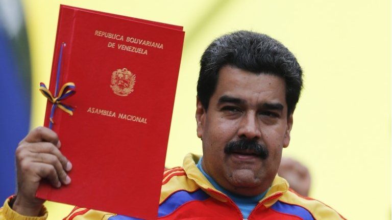 President Nicolas Maduro holds up a law document outside Miraflores Palace in Caracas on 15 March, 2015.
