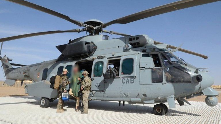 A handout picture taken and released on 6 April 2015 by the French Army and the French Defence Ministry shows two soldiers of the French special forces standing next to Dutch national Sjaak Rijke as he gets off of a Caracal Helicopter after being released.