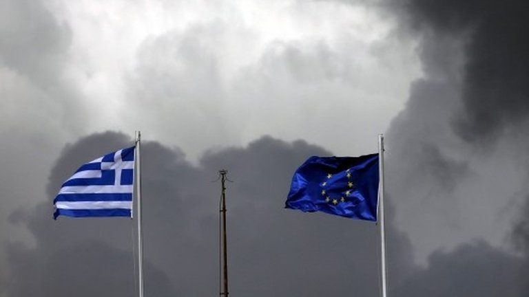 A European Union flag (R) and a Greek national flag flutter atop a building in central Athens