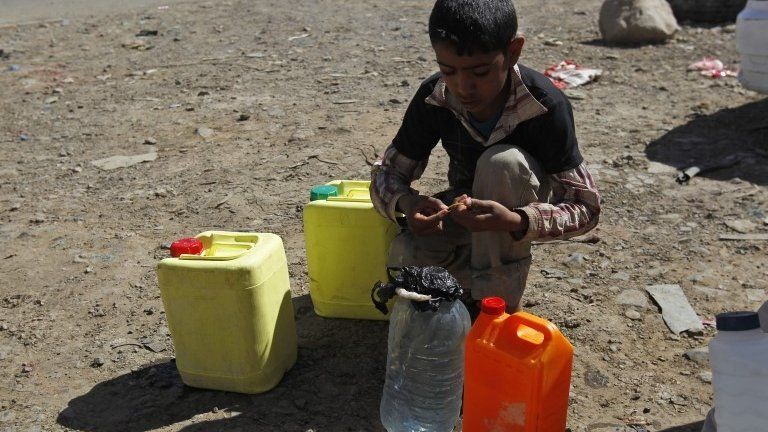 A Yemeni boy sits beside jerry cans filled with water from a philanthropist-provided water tap in Sana'a, Yemen, 16 April 2015