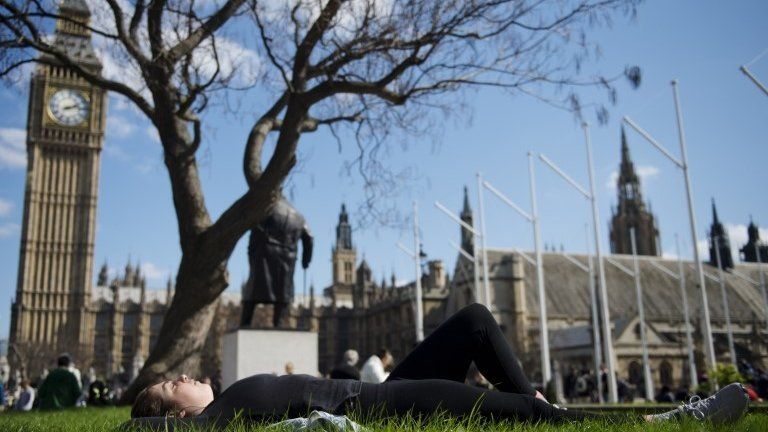 People enjoy the warm weather in Parliament Square, London
