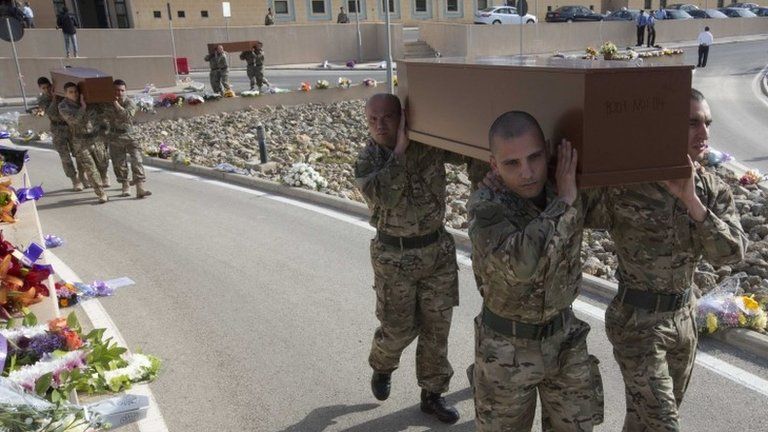 Soldiers carry coffins of some of the 24 people whose funerals were held in Malta