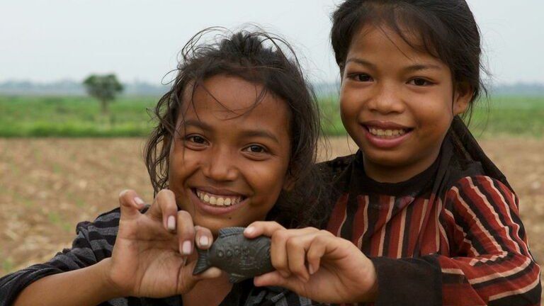 Children holding an iron fish in Cambodia