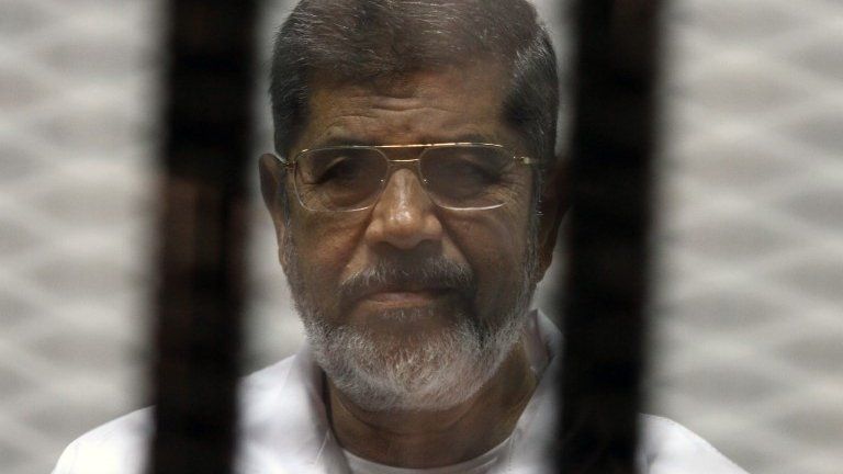 File photo: Egyptian ousted Islamist president Mohammed Morsi looking on from behind the defendants cage during his trial, 8 May 2014