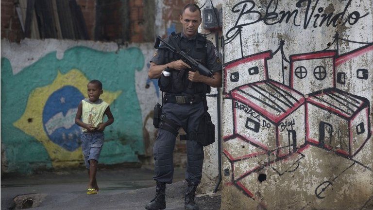 A police officer stands guard in an alley of the Alemao comple on 7 April, 2015.