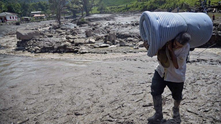 A man carries a mattress after a landslide in Salgar on 18 May, 2015.