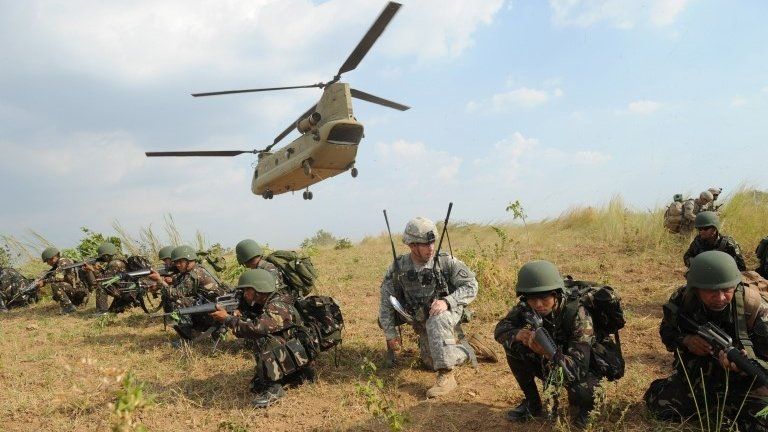 Philippine soldiers and a US army soldier from 2nd Stryker Brigade Combat of the 5th Infantry Division based in Hawaii take their positions after disembarking from a C-47 Chinook helicopter during an air assault exercise inside the military training camp of Fort Magsaysay in Nueva Ecija province north of Manila on April 20, 2015