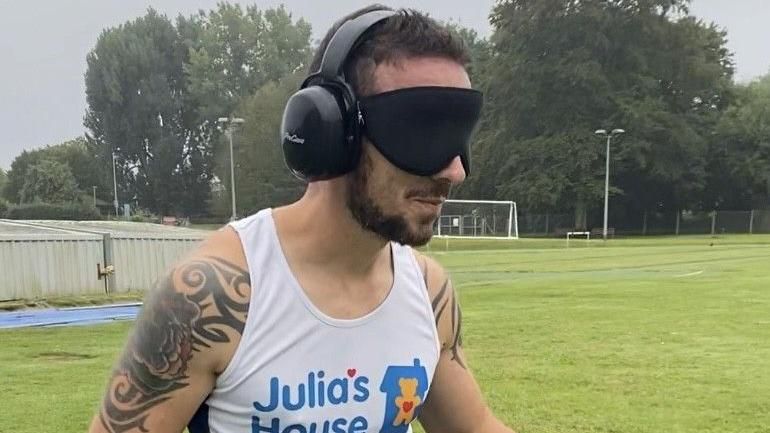 Top half of Alex Bance running with a Julia's House t-shirt, ear defenders and an eye mask