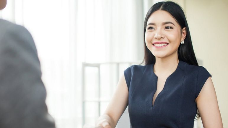 Una joven dándole la mano a un ejecutivo