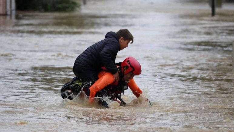 A French firefighter carries a child during rescue operations in the middle of submerged streets due to heavy rain falls and violent storm that hit Aude on 15 October 2018.