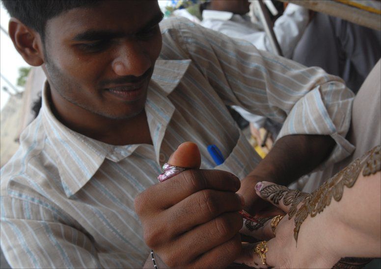 A man applies a henna design onto a woman's hand