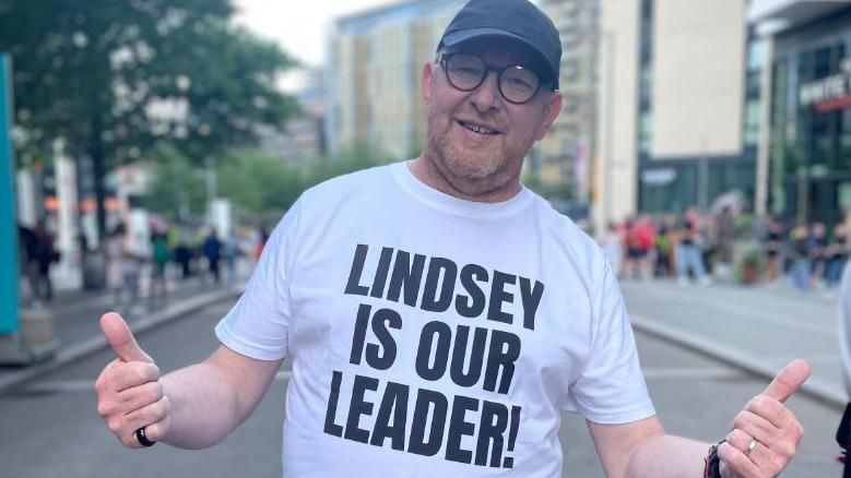 A man wearing a shirt which reads Lindsey is our leader