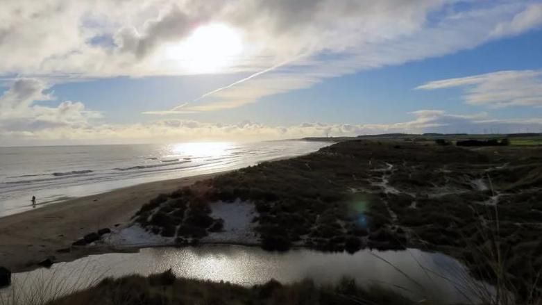 A picture of Druridge Bay with the sun shining over the water 