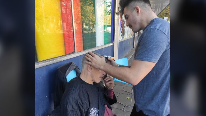 Eddie giving a man a haircut outside on the street