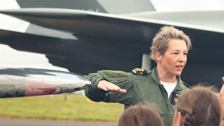 A female pilot talking to girls beside a jet 