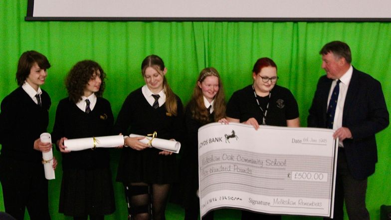 Students from Melksham Oak Community School receiving a large cheque for £500