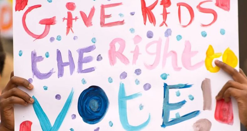 A colourful sign saying: 'Give kids the right to vote!'