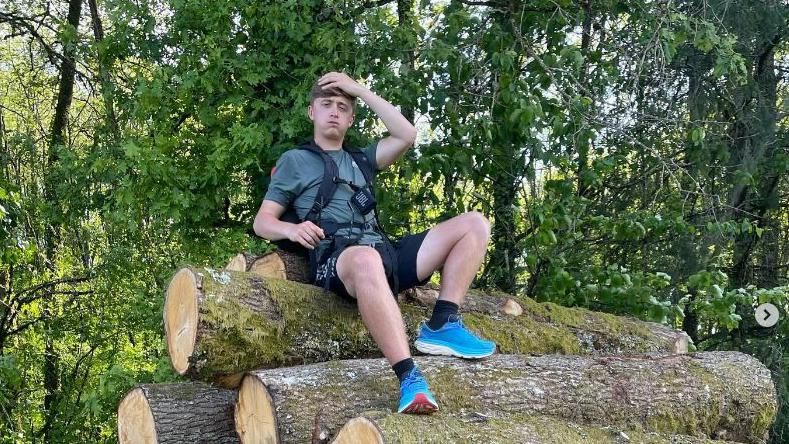 Henry Moores sat on a pile of logs, taking a break during his journey