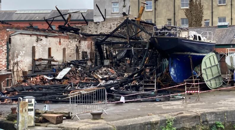 The structure of a harbourside building is reduced to rubble and burnt wood after a fire