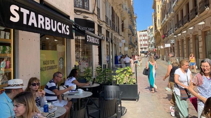 People sit outside a Starbucks in Málaga drinking coffee