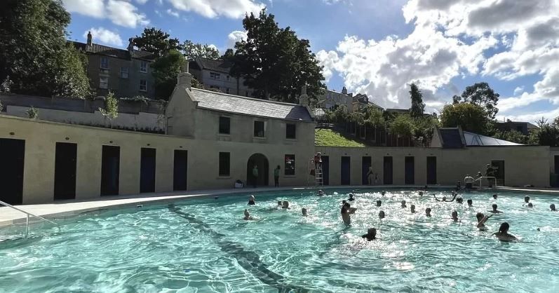 An outdoor pool with swimmers in it.