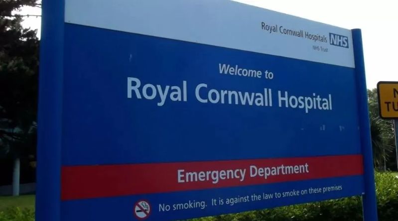 A blue, white and red sign that says 'Welcome to Royal Cornwall Hospital Emergency Department'. At the bottom of the sign another line says 'No smoking. It is against the law to smoke on these premises.'